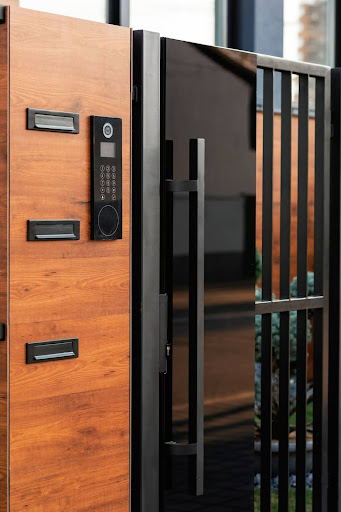 Modern wooden gate with a black keypad entry system and a sleek black handle.